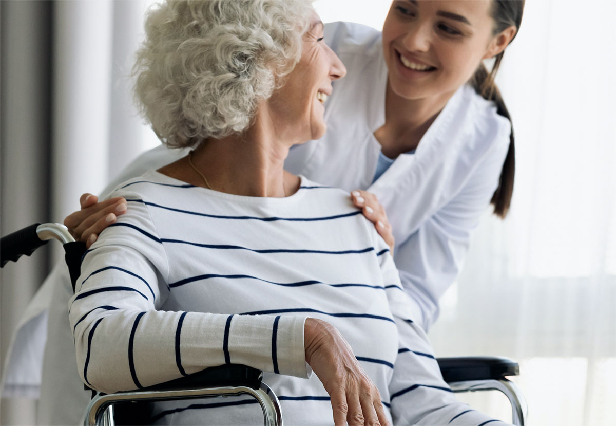A nurse helping an elderly women in a wheelchair